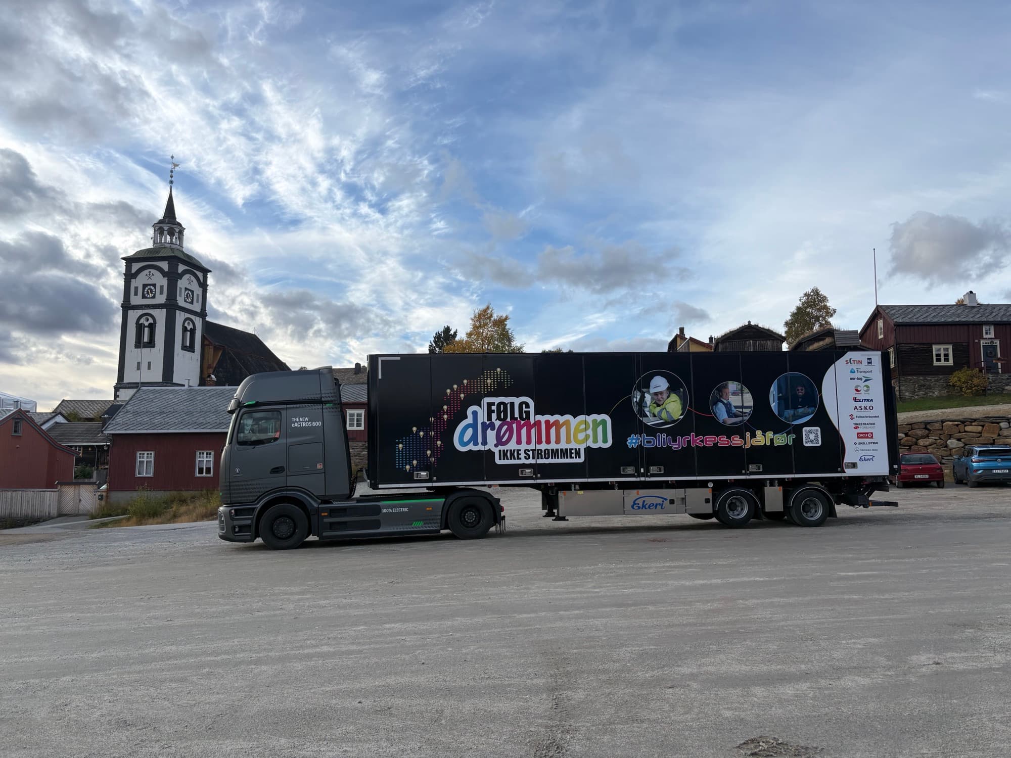 Følg drømmen-turnébilen parkert foran Røros kirke og de gamle trehusene i Bergstaden